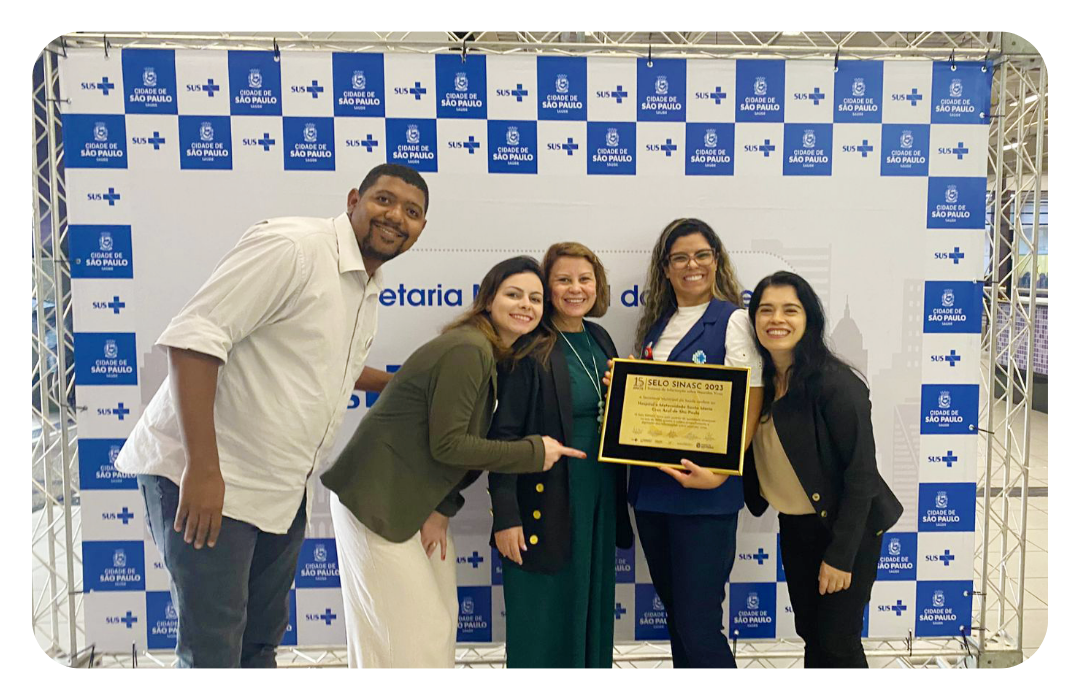 Adriana Lemes Oliveira, enfermeira chefe da Maternidade; Mauricio Gabriel Lucio Santos, assistente administrativo; Vanesa Nunes Ferreira Ribeiro, enfermeira assistencial Isabel Cristina Gomes Annino Cortez, enfermeira assistencial; Katia da Silva Dias Assunção, enfermeira obstétrica segurando o Selo Nível Ouro sinasc 2023 do Hospital Cruz Azul